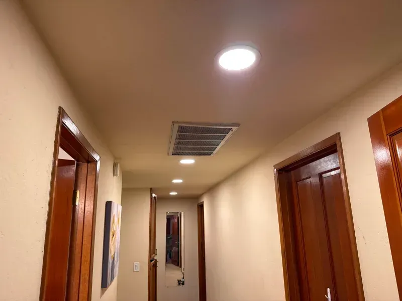 Hallway with recessed lighting, brown doors, and a ceiling vent.