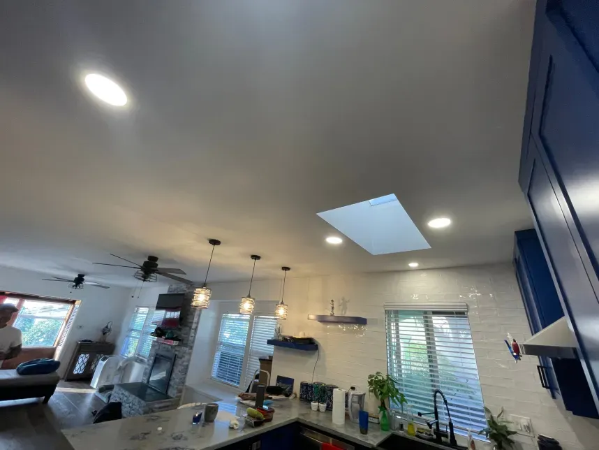 Blue kitchen with pendant lights, a skylight, and stainless steel appliances.