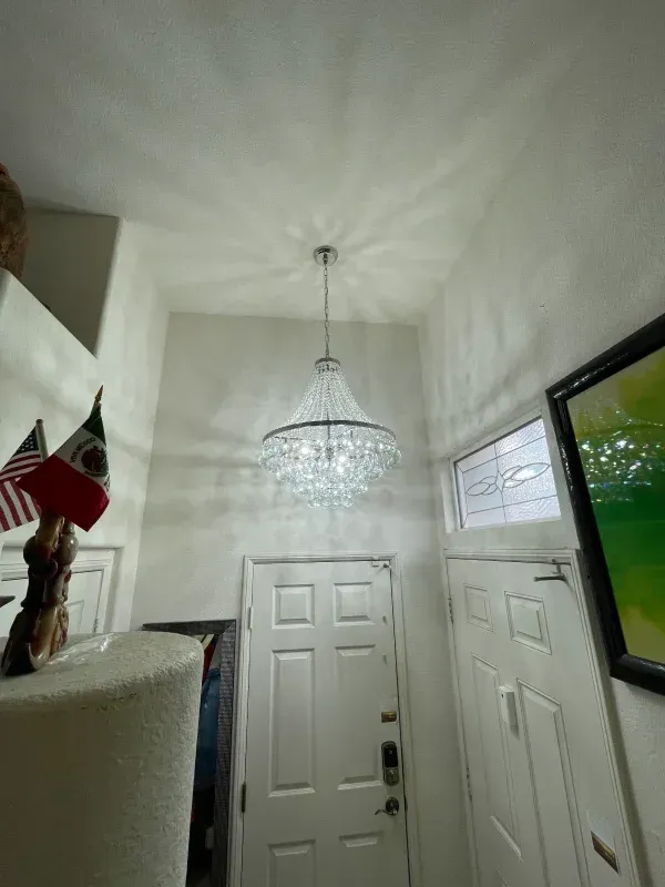 Chandelier hanging above a white door in a narrow hallway. Flags and artwork are also visible.