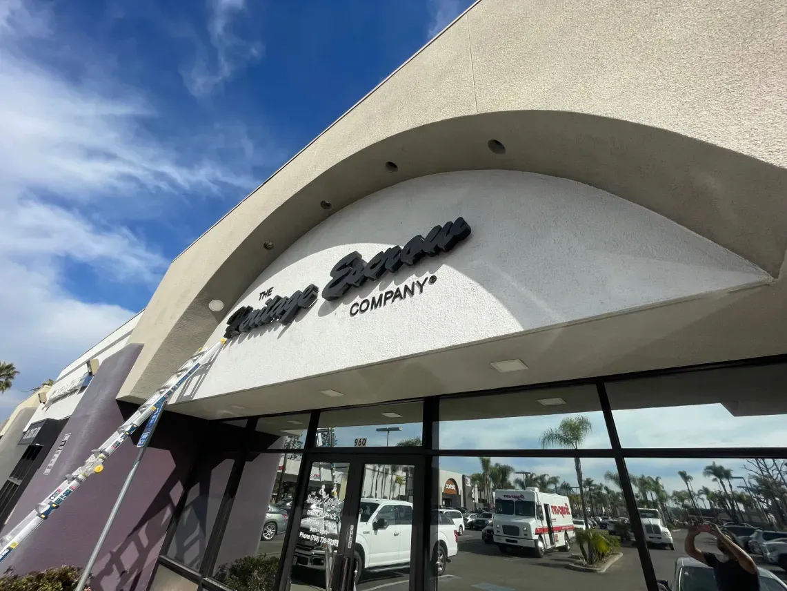 Exterior of The Rolling Stone Company store with black lettering on white facade, blue sky.