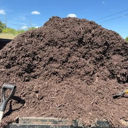 Pile of dark brown mulch with a shovel resting in front.