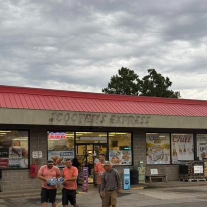 Scooter's Express convenience store exterior; people walking in front, overcast sky. Red roof, brick building.