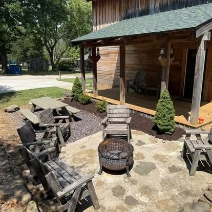 Patio with wooden furniture, fire pit, picnic table, and cabin in the background.