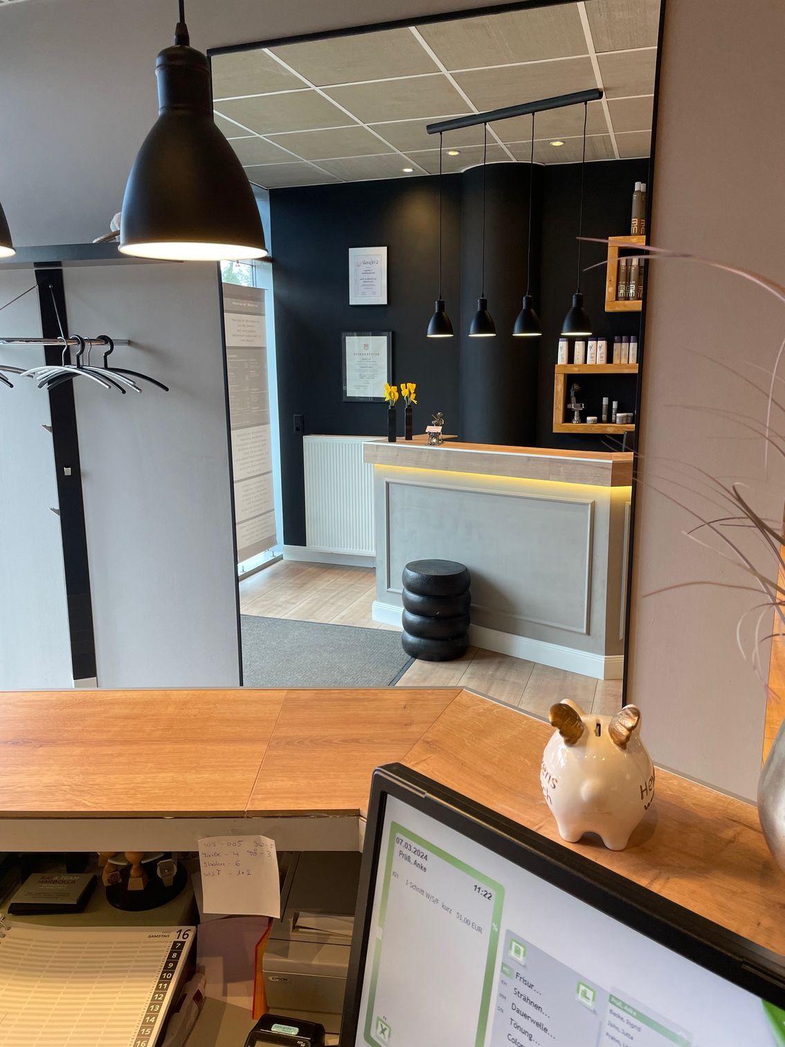 Ein Sparschwein steht auf einem Schreibtisch neben einem Computermonitor.