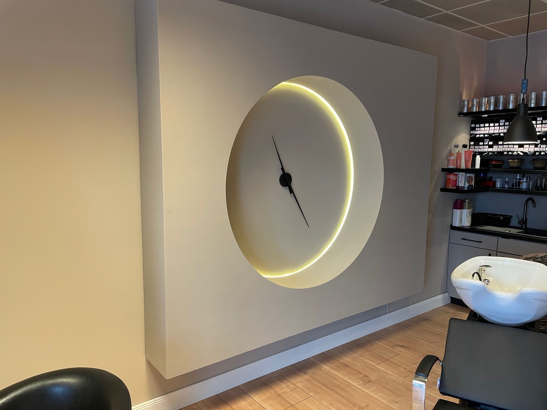 Ein Salon mit einer Uhr an der Wand und einem Waschbecken