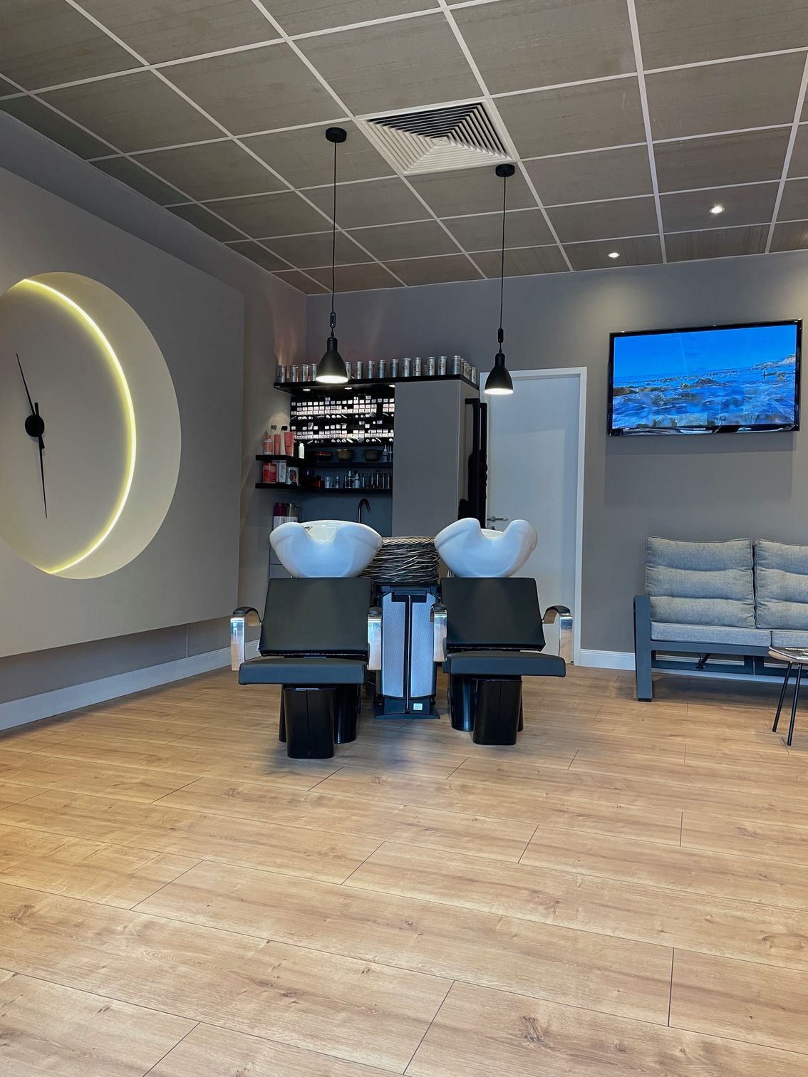 Ein Salon mit zwei Waschbecken und einem Fernseher an der Wand.