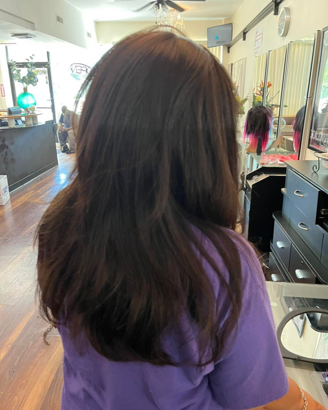 A woman with long curly hair is standing in front of a mirror.