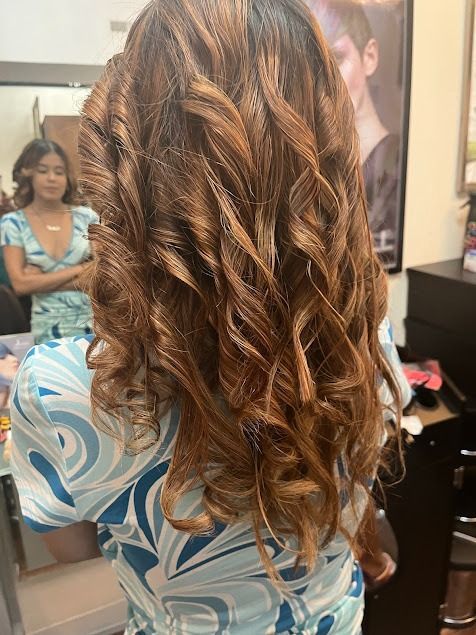 A woman with long curly hair is standing in front of a mirror.