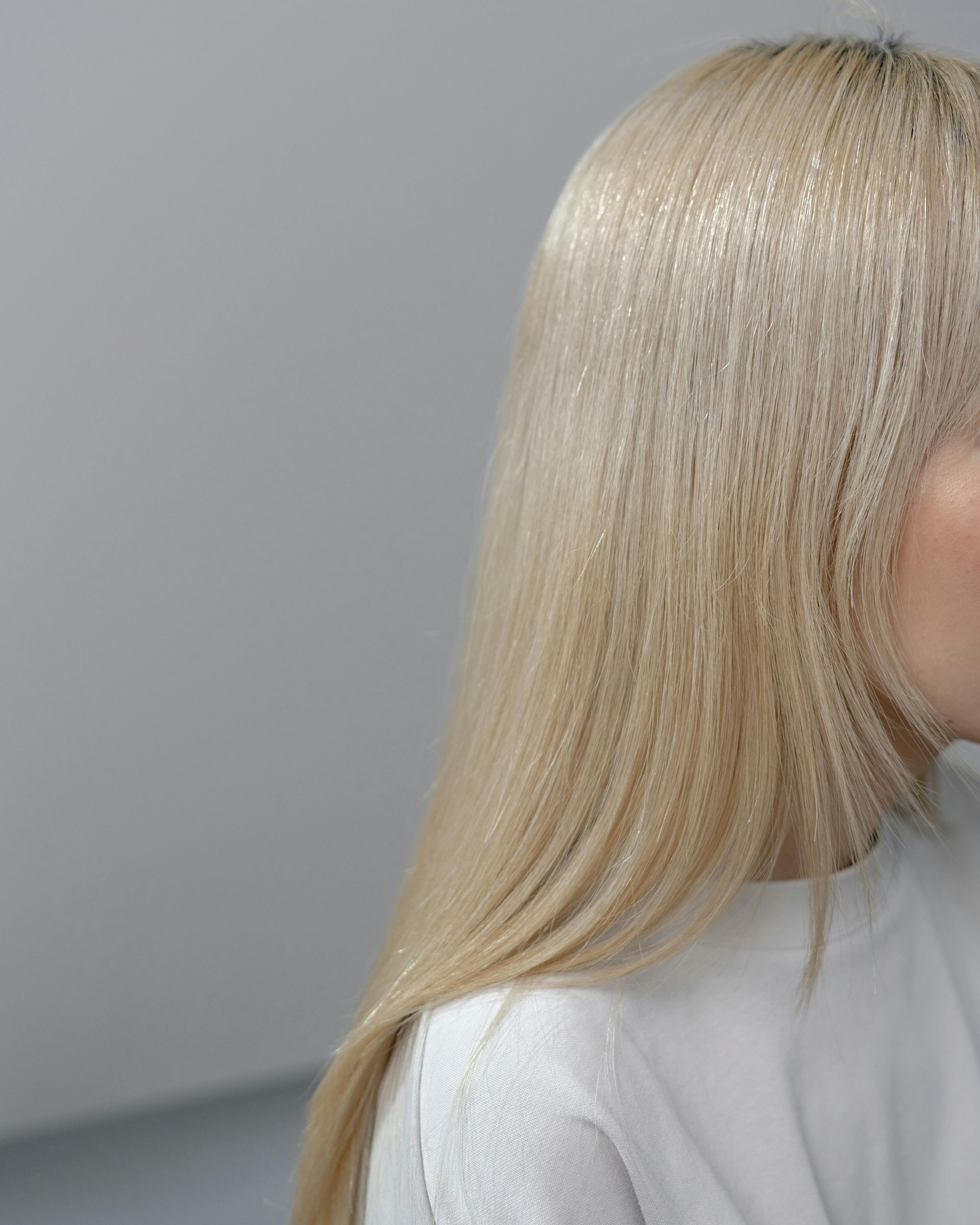 A woman with long blonde hair is wearing a white sweater.