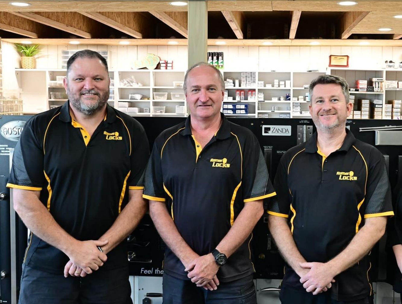 Three Men Are Posing For A Picture In A Store — Port Macquarie Locksmiths In Port Macquarie, NSW