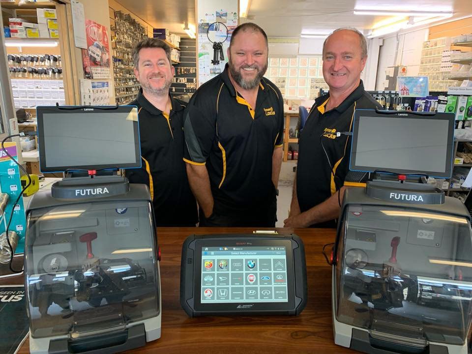 Three Men Are Standing In Front Of A Table With Three Computers On It — Port Macquarie Locksmiths In Port Macquarie, NSW