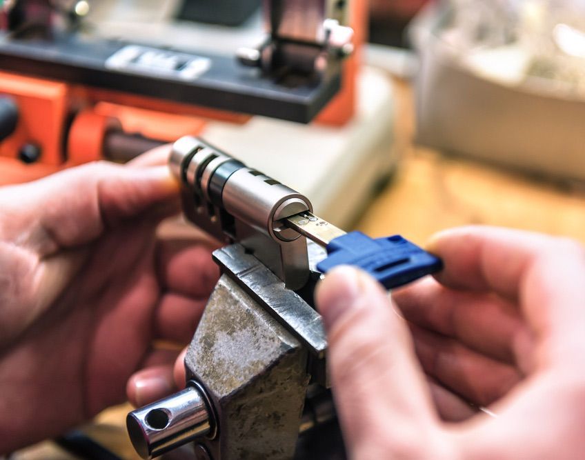 A Person Is Cutting A Key With A Machine — Port Macquarie Locksmiths In Port Macquarie, NSW