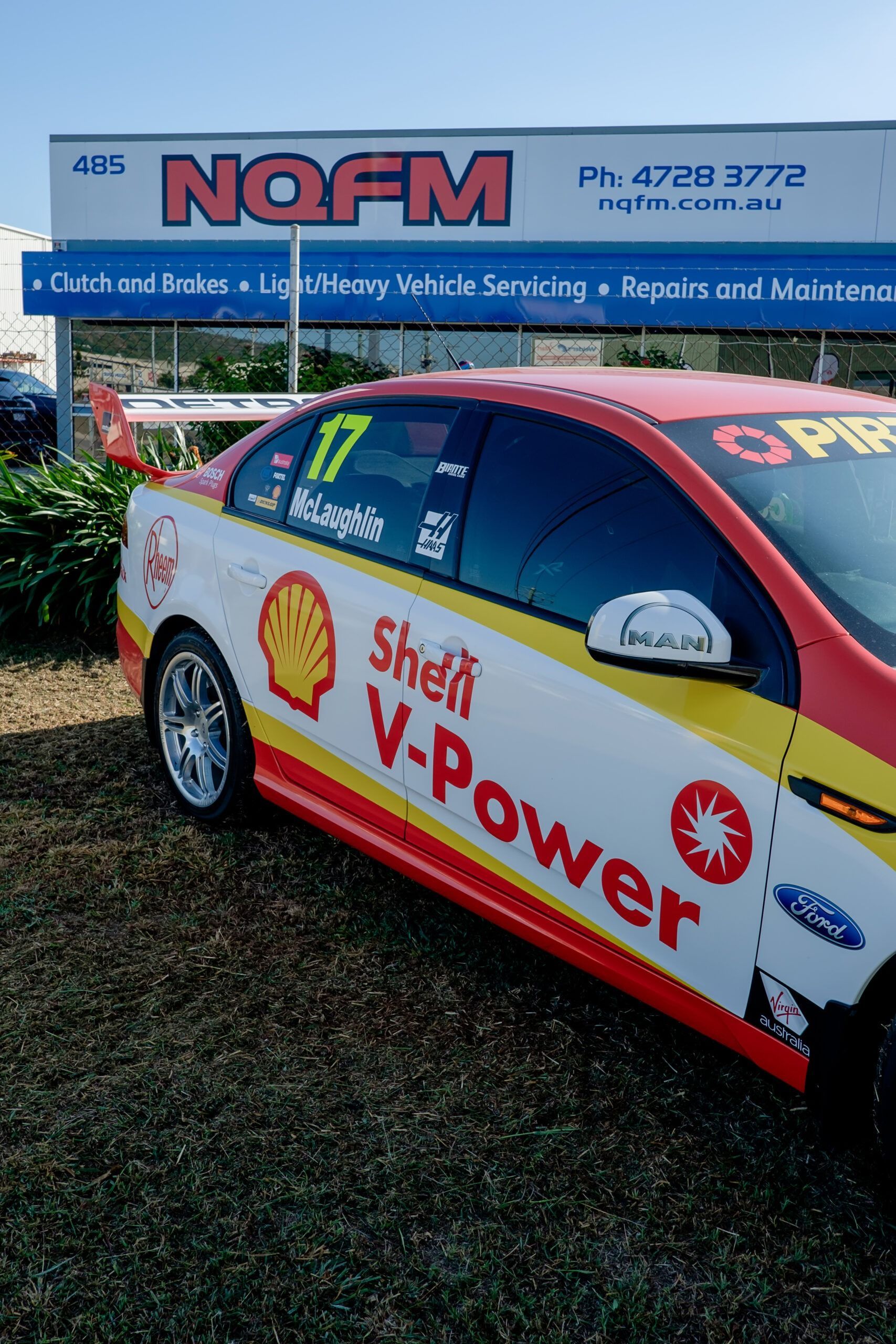 A shell v-power car is parked in front of a nofm sign
