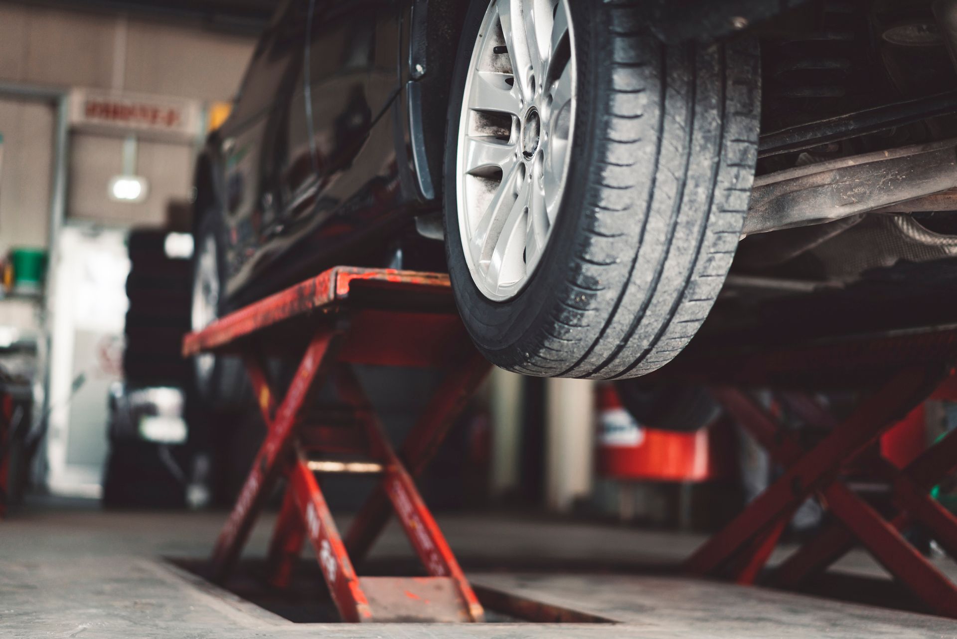 A car is sitting on a lift in a garage.