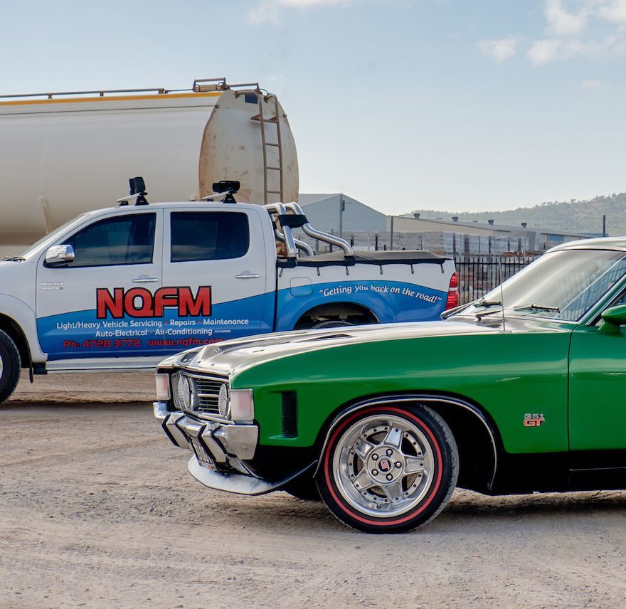 A nofm truck is parked next to a green car
