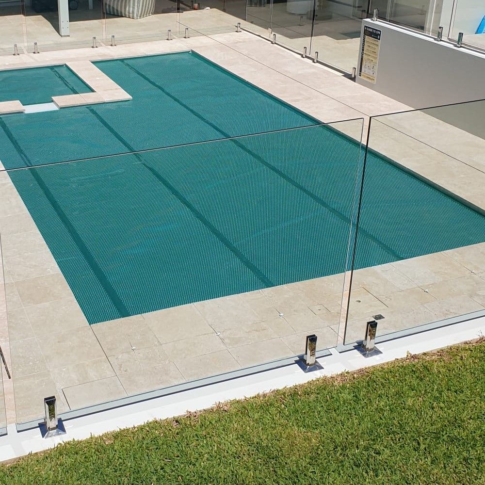 Pool With a Teal Cover, Surrounded by Glass Fencing and Light-colored Stone — Aussie UnderCover In South Nowra, NSW