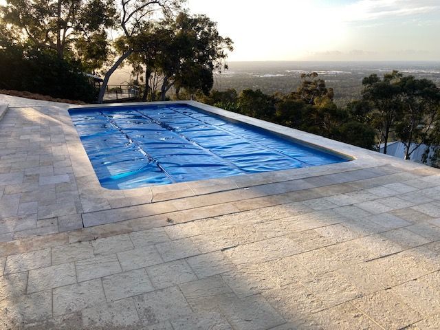 A Large Swimming Pool With A Blue Cover On It Is Surrounded By Trees — Aussie UnderCover In Melbourne, VIC