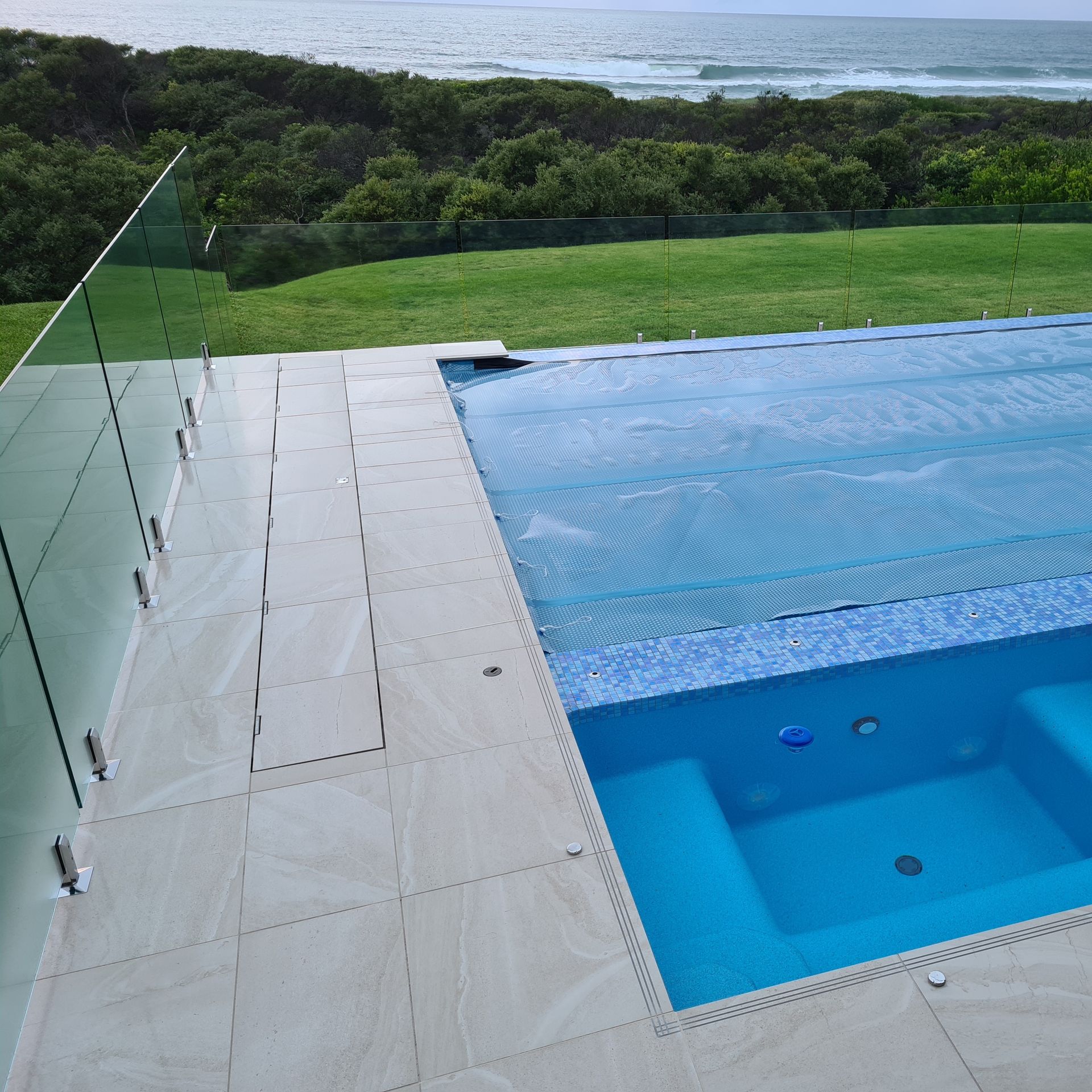 Pool with clear glass fencing overlooks the ocean and green landscape — Aussie UnderCover In South Nowra, NSW