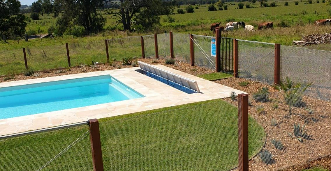 A Swimming Pool Surrounded By Grass And A Chain Link Fence — Aussie UnderCover In Gold Coast, QLD