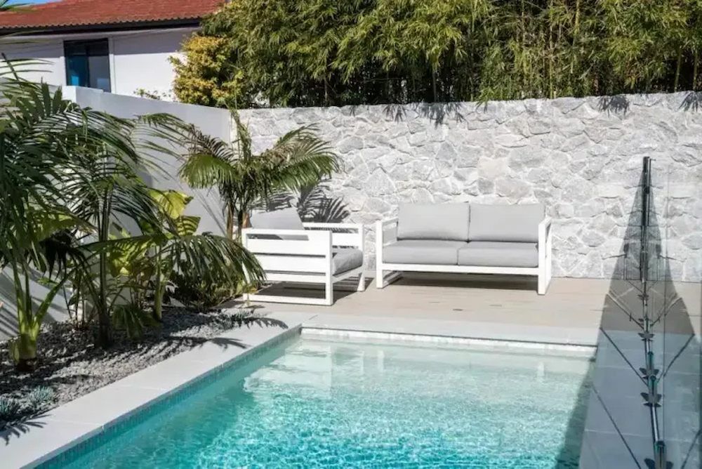 A couch and chair are sitting next to a pool.