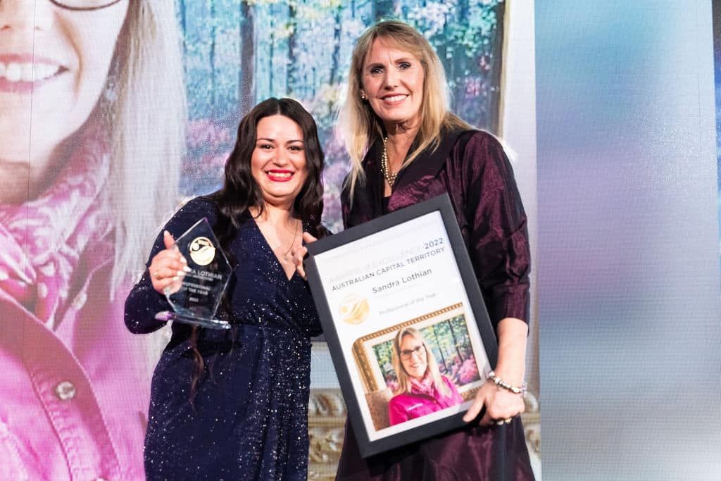 Two Women Are Standing Next To Each Other On A Stage Holding Awards — Aussie UnderCover In South Nowra, NSW