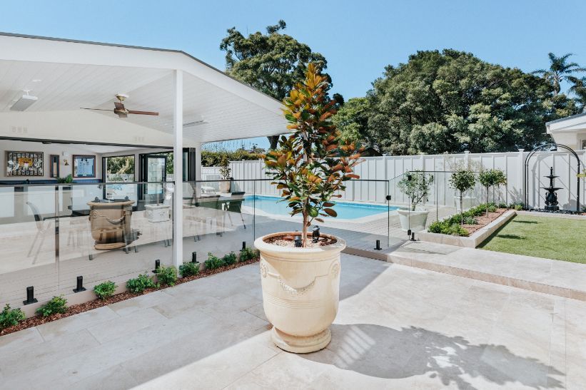 A Potted Plant is Sitting on a Patio Next to a Pool — Aussie UnderCover In South Nowra, NSW
