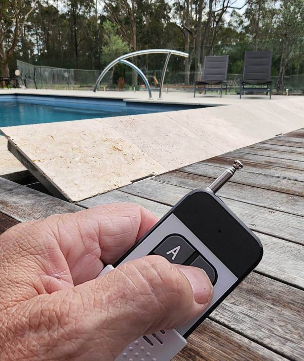 A person is holding a remote control in front of a swimming pool — Aussie UnderCover In South Nowra, NSW