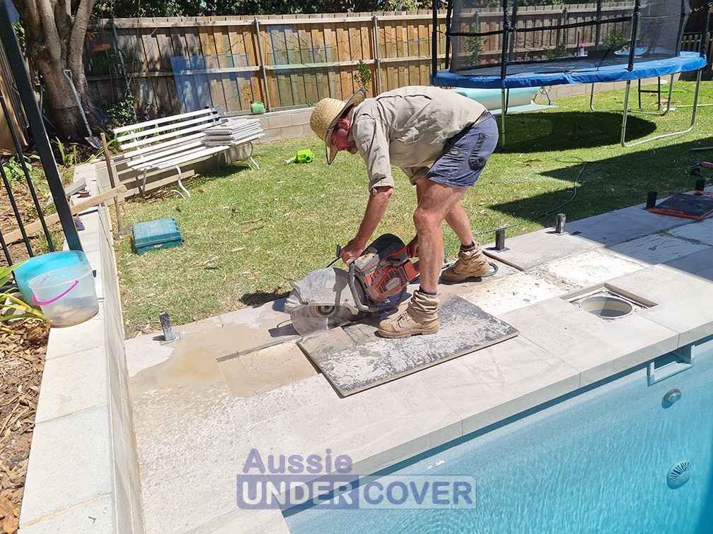 A Man Is Cutting Concrete Next To A Pool With A Circular Saw — Aussie UnderCover In South Nowra, NSW