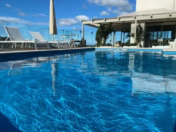 A Large Swimming Pool Surrounded By Chairs And Umbrellas On A Sunny Day — Aussie UnderCover In South Nowra, NSW