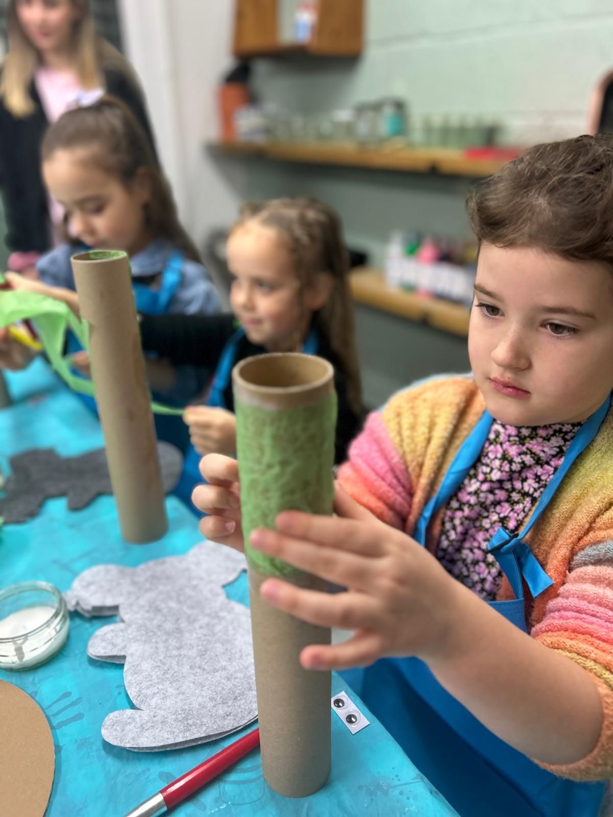 A little girl is holding a cardboard tube in her hands at Dragonfly crafts 