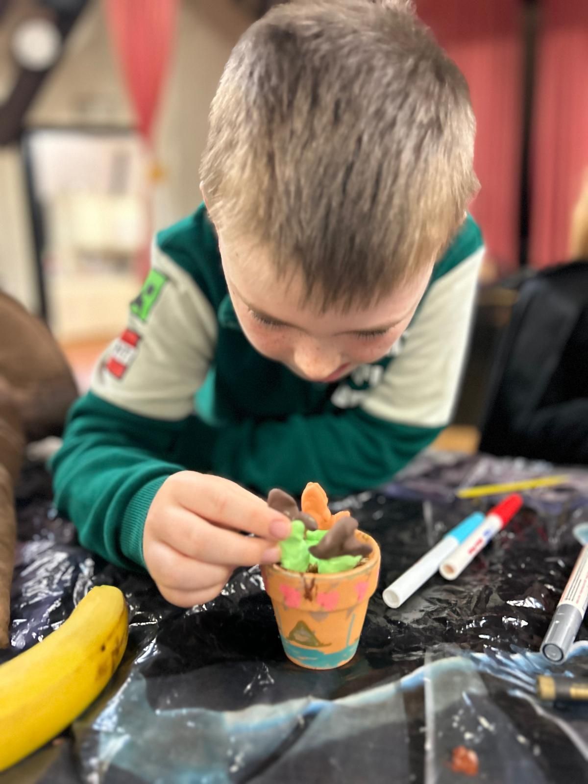 A young boy in a green shirt is playing with clay at Dragonfly crafts
