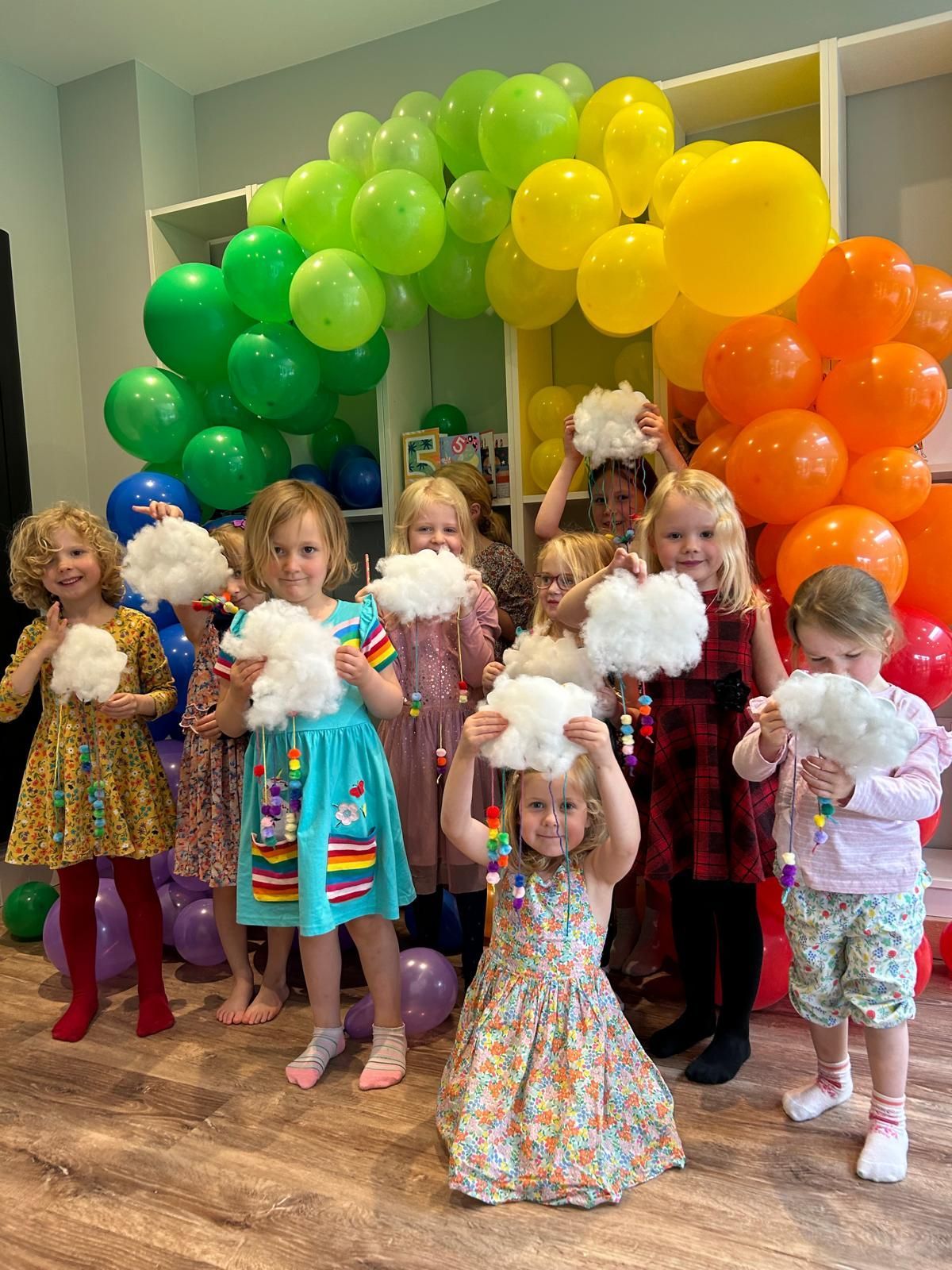A group of children are holding cotton candy in front of balloons at Dragonfly crafts