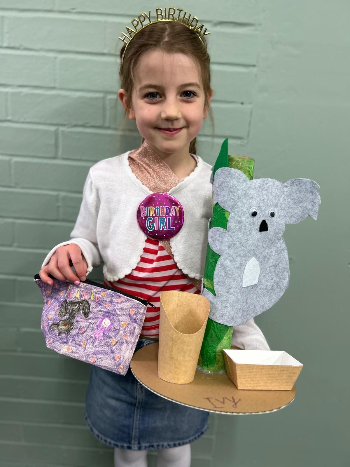 A little girl is holding a tray with a koala on it at Dragonfly-craft parties.