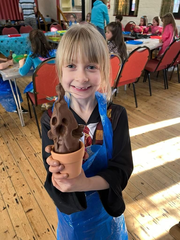 A young girl is holding a potted plant in her hands at Dragonfly crafts party