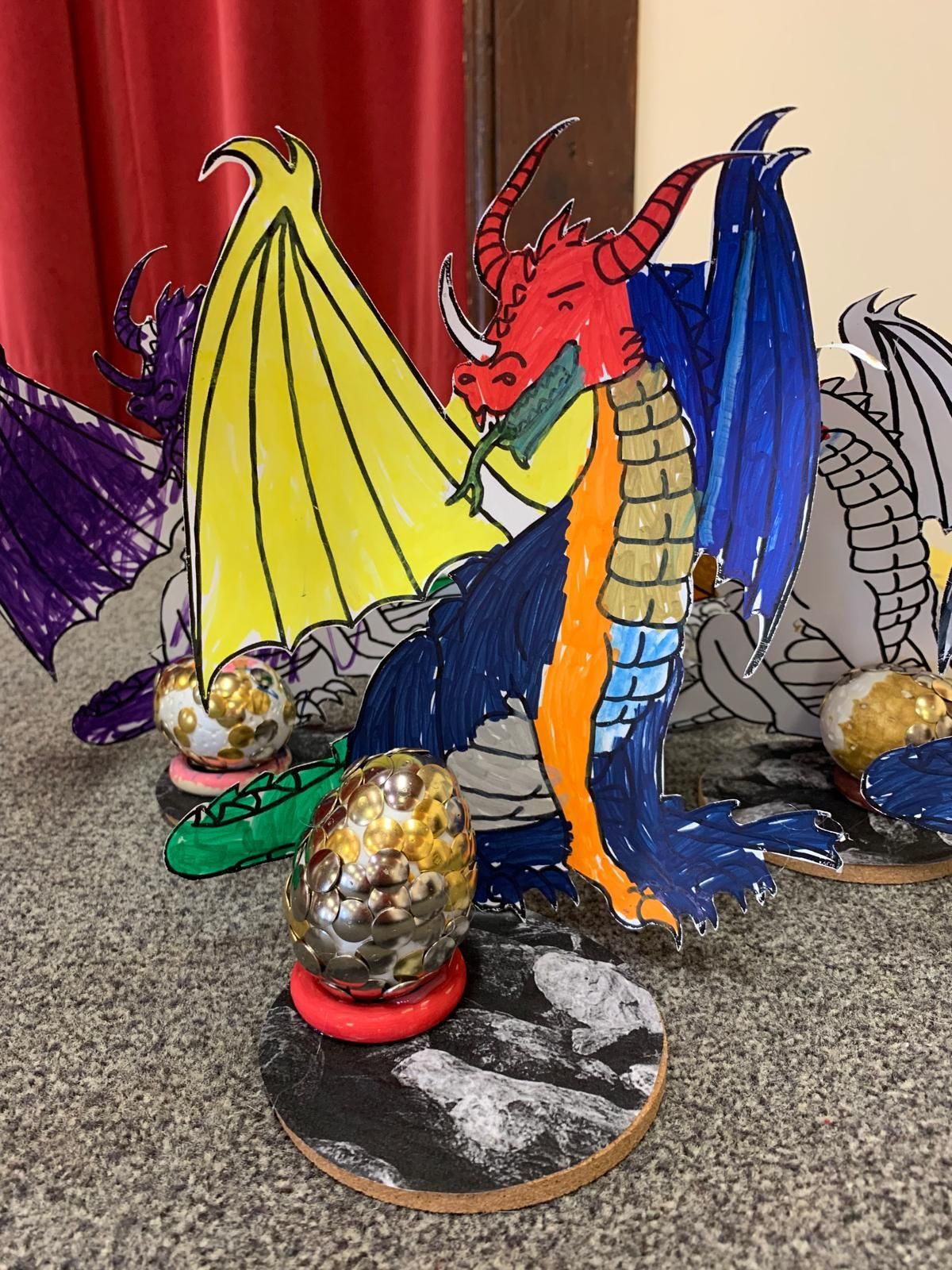 A drawing of a dragon is sitting on a table next to some balls for Dragonfly crafts party
