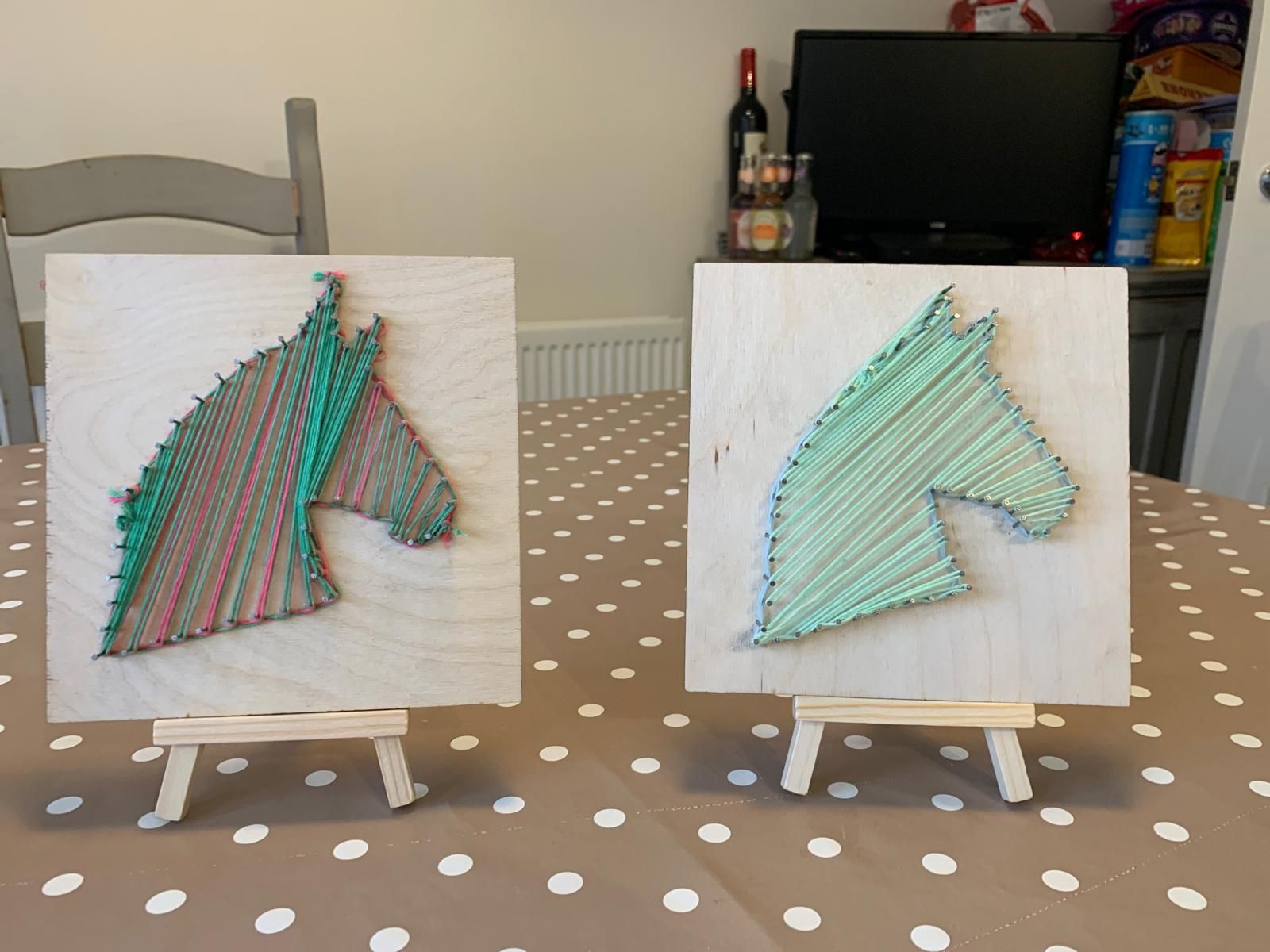Two string art horse heads are sitting on a table for at Dragonfly craft parties.