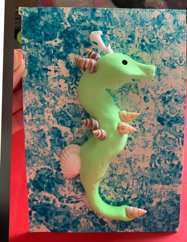 A green seahorse with seashells on its back at Dragonfly-craft parties.