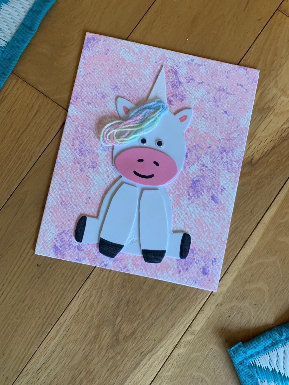 A picture of a unicorn sitting on a wooden floor or craft party