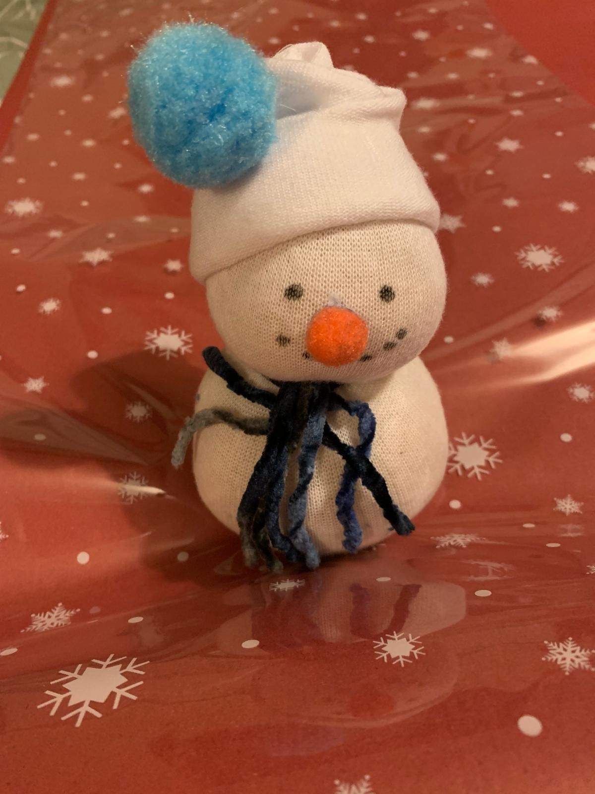 A sock snowman with a white hat and blue pom pom for Dragonfly crafts party