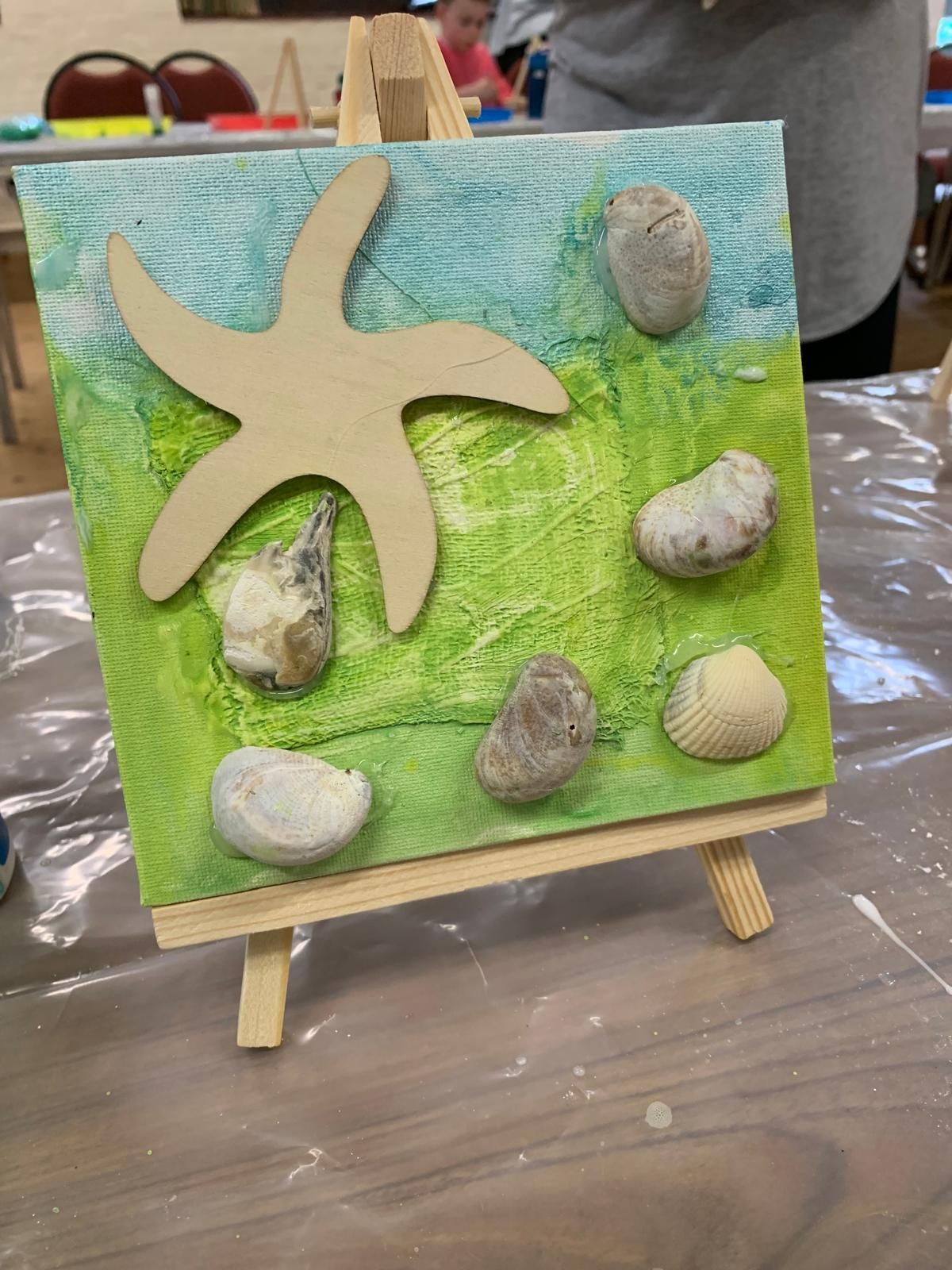 A painting of a starfish and seashells on a table for Dragonfly crafts party.