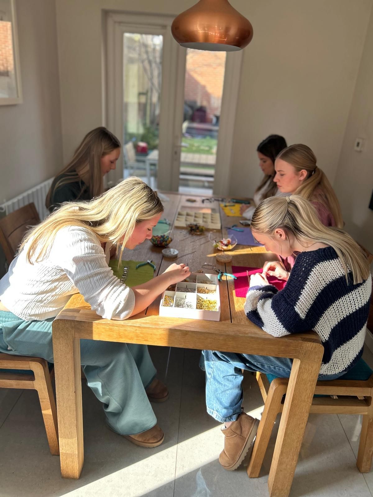 A group of women are sitting at a table in a room for charm party at Dragonfly crafts parties