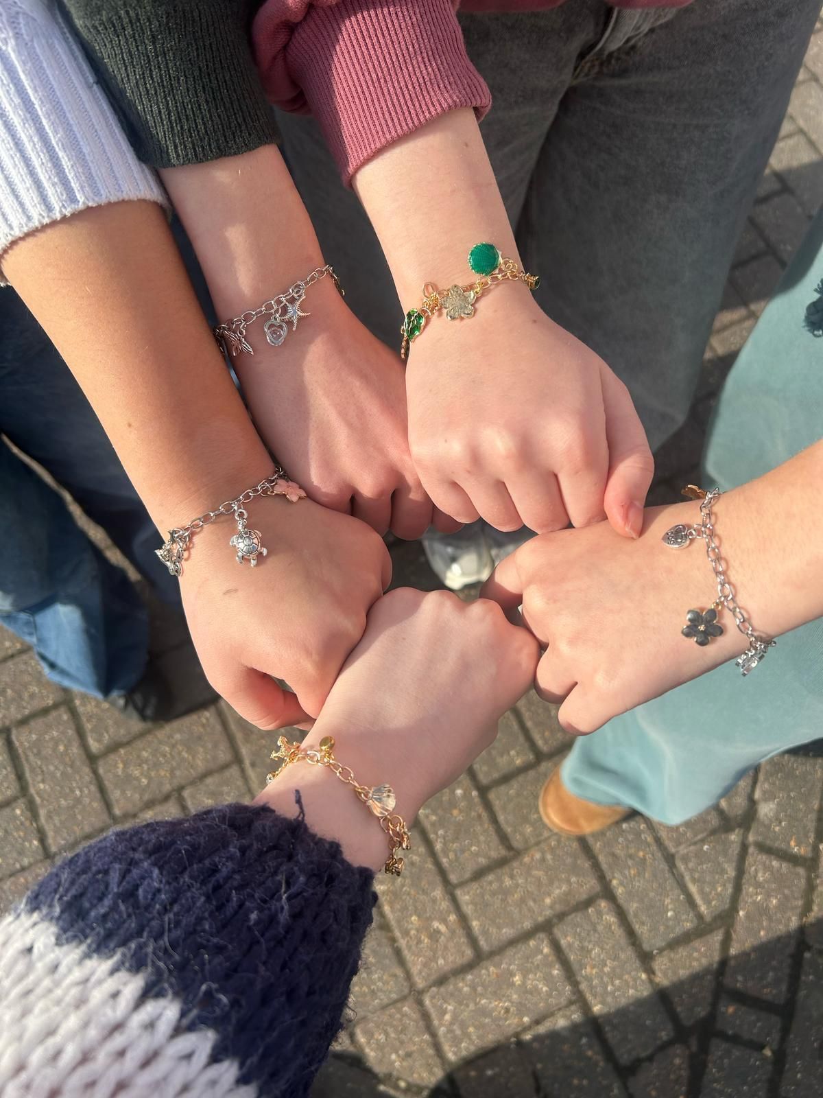 A group of people wearing bracelets on their wrists for charm party at Dragonfly crafts parties