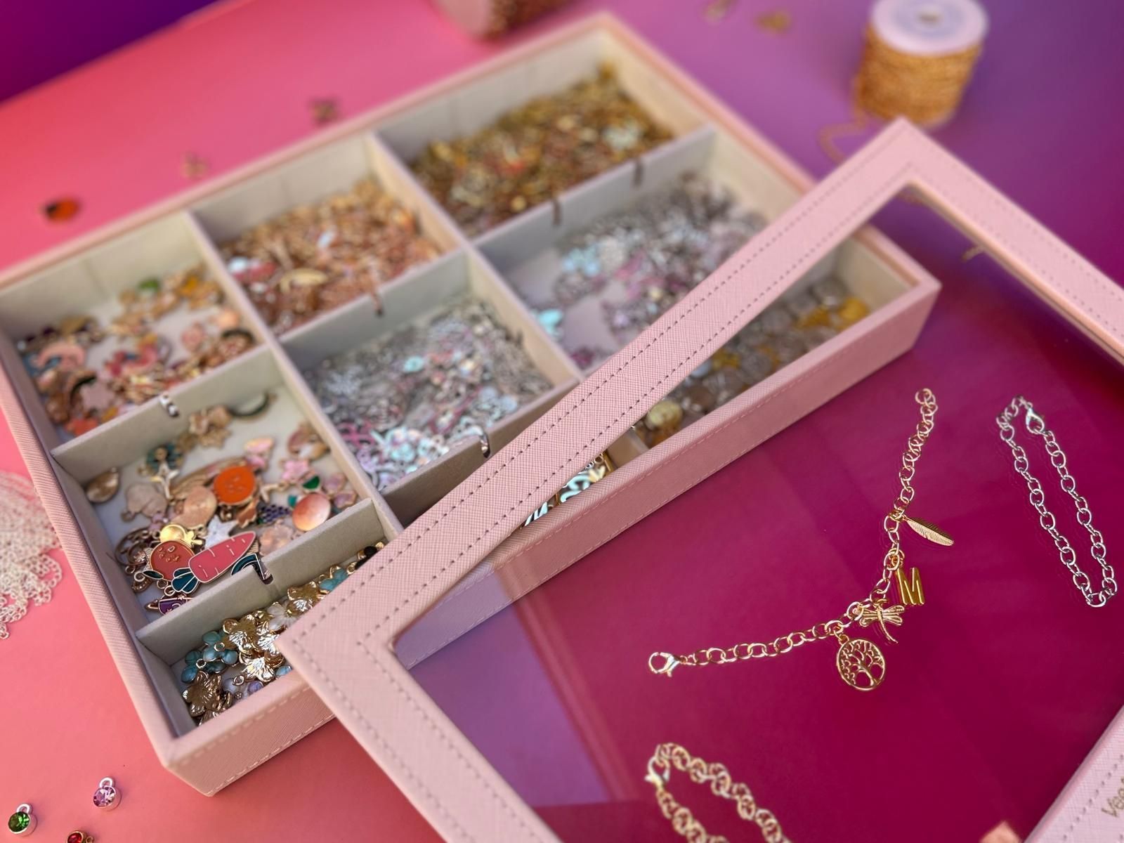 A pink jewelry box with a clear lid filled with jewellery for charm party at Dragonfly crafts parties