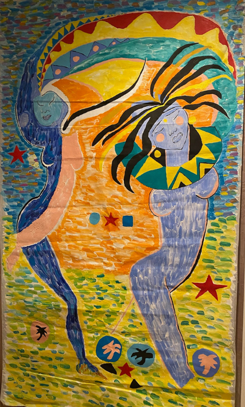 A colorful painting of two women hugging each other on a wall.