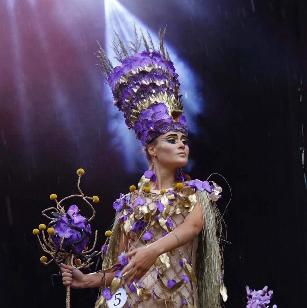 Una donna in costume viola e oro con il numero 5 sul braccio