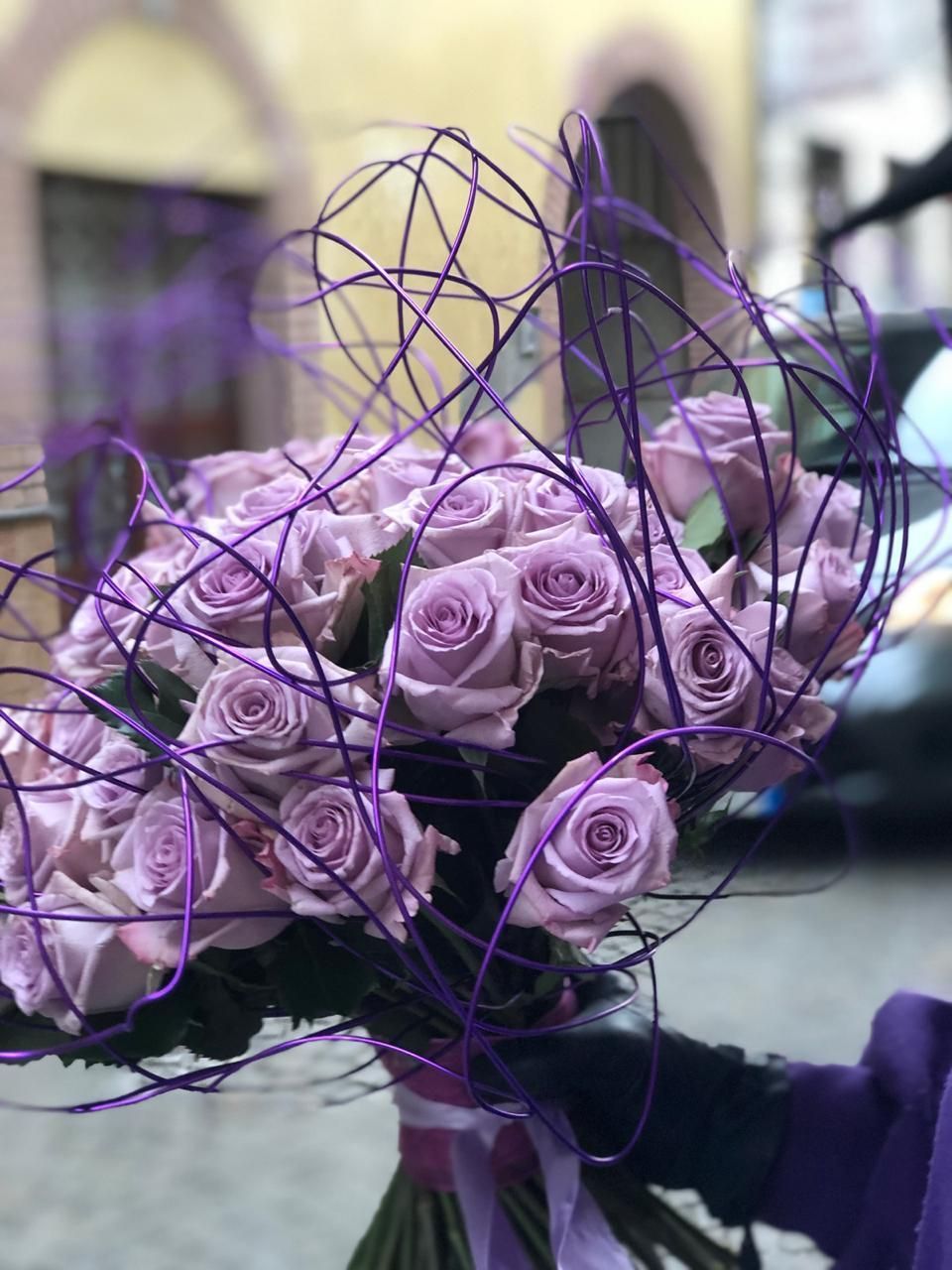 Una persona tiene in mano un grande mazzo di rose viola.