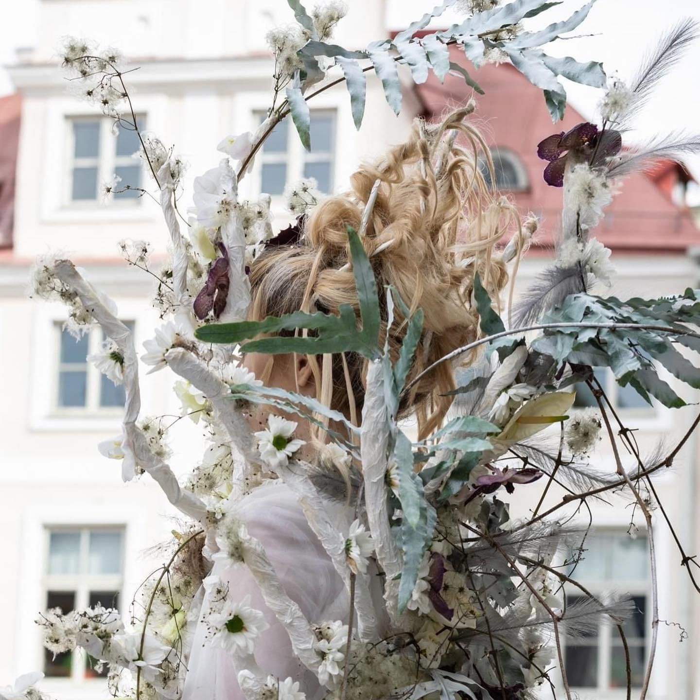 Una donna tiene in mano un mazzo di fiori davanti a un edificio.