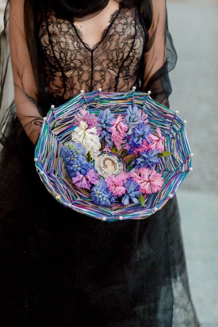 Una donna con un abito nero tiene in mano una ciotola di fiori.