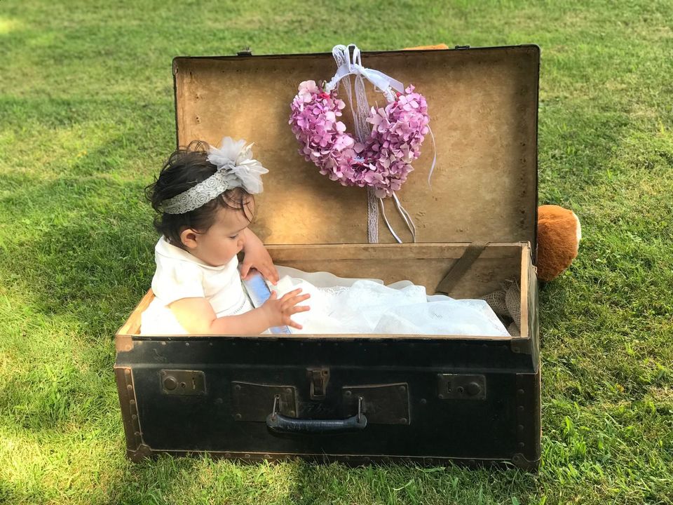 Una bambina è sdraiata in una valigia sull'erba.
