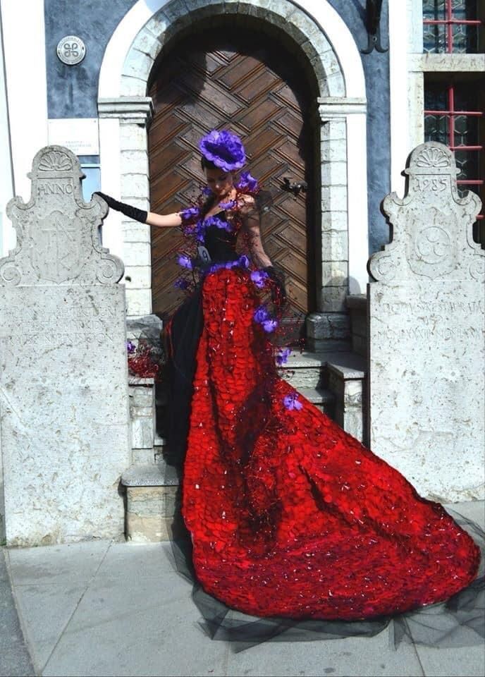 Una donna con un lungo vestito rosso è in piedi davanti a una porta